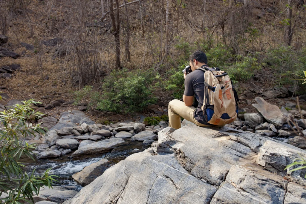 Budget traveler photographing scenic creek and rocky landscape in Zion National Park