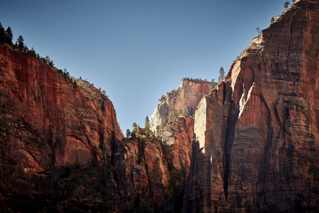 Towering red sandstone cliffs in Zion National Park under a clear blue sky in Southern Utah