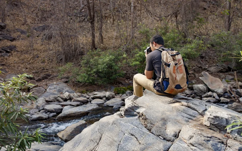 Budget traveler photographing scenic creek and rocky landscape in Zion National Park